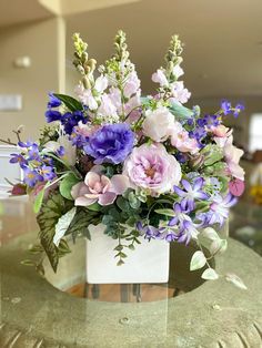 a vase filled with purple and white flowers on top of a table