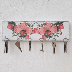 there is a key holder with flowers on it and five keys hanging from the hooks