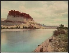 an old photo of a river with mountains in the back ground and clouds in the sky