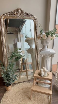 a large mirror sitting on top of a wooden table next to a vase filled with flowers