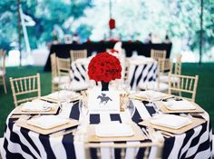 a black and white table cloth with red flowers in a vase on the centerpiece