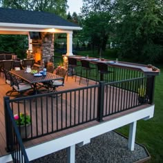 a deck with table and chairs next to an outdoor kitchen