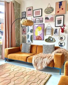 a living room with orange couches and pictures on the wall above them, along with rugs