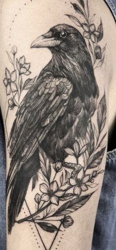 a black bird sitting on top of a branch with leaves and flowers in it's beak