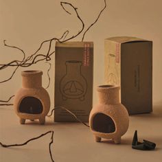 two ceramic vases sitting next to each other near a box and twig on the ground