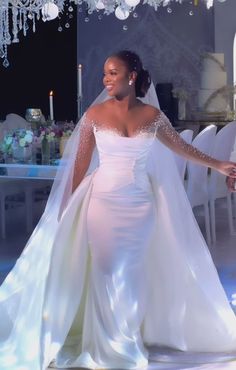 a woman in a white wedding gown and veil walking down the aisle with her hand on her hip