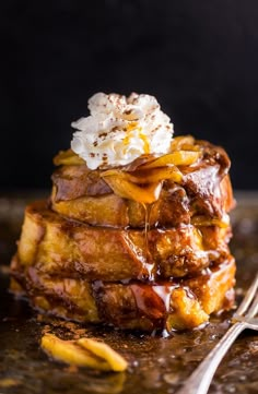 a stack of french toast with syrup and whipped cream on top, sitting on a plate