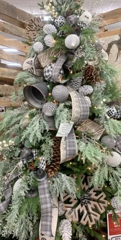 a christmas tree decorated with plaid and silver ribbon, pine cones, snowflakes and ornaments