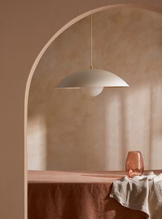 an arch in a room with a table and vase on it, next to a lamp hanging from the ceiling