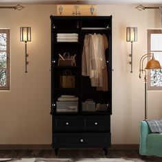 a black armoire with clothes hanging on it in a room next to a couch