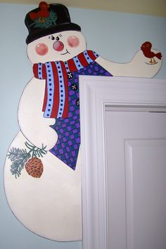 a snowman painted on the wall next to a white door with pineconis