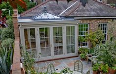 an enclosed patio with tables and chairs in the middle of it, surrounded by greenery