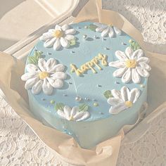 a blue cake decorated with white flowers and the words happy on it in gold lettering