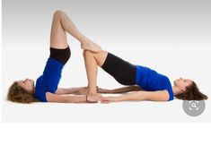 two women are doing yoga on their stomachs and legs, one is holding the other's leg