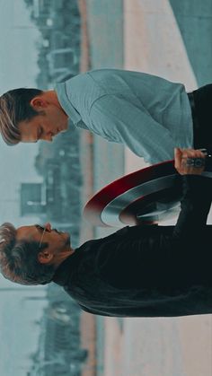 two men standing next to each other in front of a window with the captain's shield on it