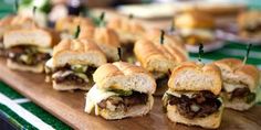 several mini sandwiches are lined up on a cutting board with toothpicks in them