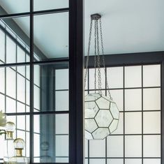 a chandelier hanging from the side of a window in a room with large windows