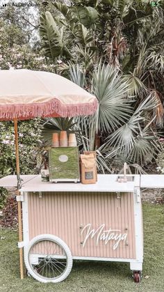 an outdoor ice cream cart with umbrella and plants in the background