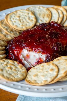 a plate with crackers, cheese and jelly spread on it next to some crackers