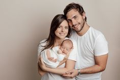 a man and woman holding a baby in their arms