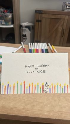 a birthday card with candles on it sitting on a table next to colored crayons