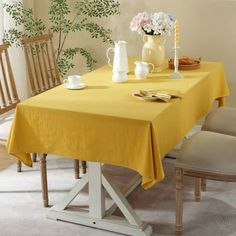 a dining room table with yellow linens and white chairs