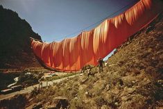 two people are standing on the side of a hill with orange tarp covering it