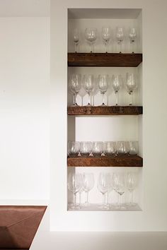 wine glasses are lined up on wooden shelves