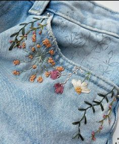 a pair of jeans with embroidered flowers on them