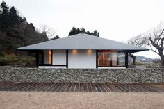 a white house sitting on top of a lush green hillside next to a stone wall