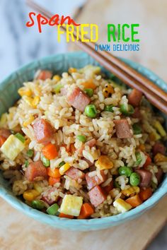 a bowl filled with rice and vegetables next to chopsticks