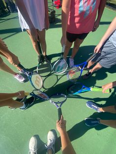 a group of people holding tennis racquets on top of a tennis court