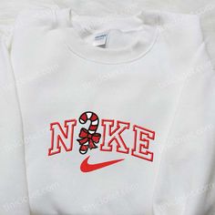 Introducing the Candy Cane x Nike Embroidered Sweatshirt, a festive fusion of comfort and style. This limited edition collaboration features a striking candy cane embroidery on a premium Nike sweatshirt. Made with high-quality materials, this sweatshirt guarantees supreme comfort and durability. The Nike Inspired Embroidered Shirt is a must-have for any sneakerhead. With its unique [...] Nike Box Christmas Tree, Rhinestone Nike Sweatshirt, Cute Sweat Shirt Nike, Candy Cane Nike Sweatshirt, Nike Sweatshirts Svg, Strawberry Nike Sweatshirt, Astetic Nike Sweatshirt, Custom Nike Sweatshirt Christmas, Nike Christmas Clothes