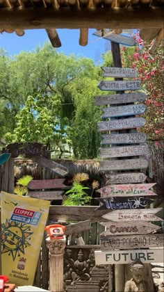 several wooden signs hanging from the side of a building in front of trees and bushes