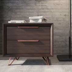 a brown wooden dresser with two drawers and some books on top of it next to a brick wall