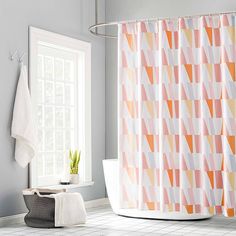 a bathroom with an orange and white shower curtain next to a bathtub in front of a window