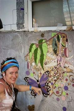 a woman with headbands is pointing at a butterfly on a wall