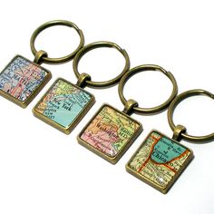 four key chains with different maps on them, one is gold and the other is blue