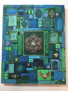 a green and blue square with many different designs on it's sides, including an ornate brooch