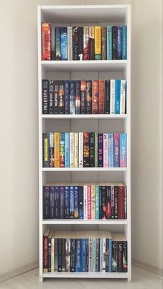 a book shelf filled with lots of books on top of white shelves next to a wall