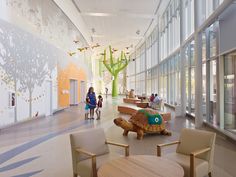 people are walking through the lobby of an animal - themed building with large glass windows