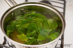 green leaves are being cooked in a pot on the stove