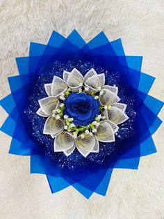 an overhead view of a blue and white paper flower on a fluffy carpeted surface