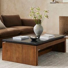 a living room with a couch, coffee table and vase on the top of it