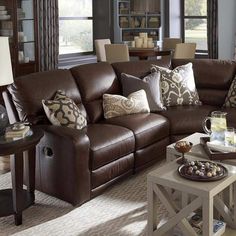 a living room filled with lots of furniture and pillows on top of a brown couch