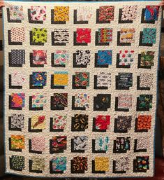 a person holding up a quilt made with squares and dots on the back of it