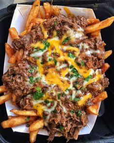 a tray filled with french fries covered in cheese and meat