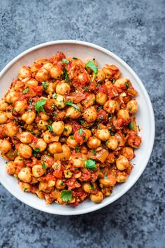 a white bowl filled with chickpeas covered in tomato sauce