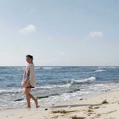 a woman is walking on the beach near the water