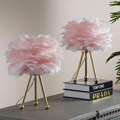 two pink lamps on top of a table next to a book